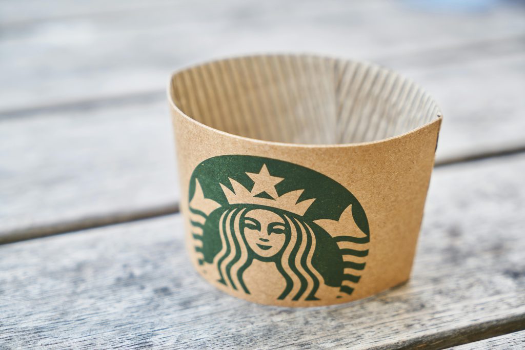 Close-up of a cardboard coffee sleeve on a wooden table, showcasing eco-friendly design in a classic coffee setting.